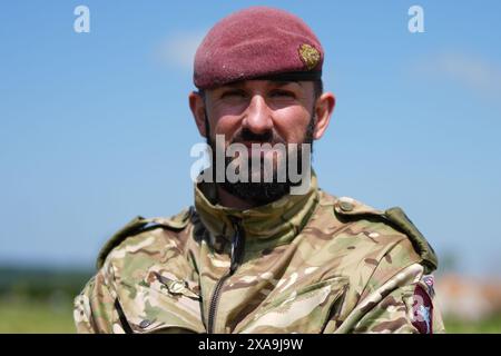 Le capitaine Maik Biggs, du 16e Régiment médical, dont le grand-père a combattu pour les nazis pendant la seconde Guerre mondiale, pose après avoir participé à un saut en parachute aux côtés de membres des forces armées britanniques, belges, canadiennes et américaines, organisé par la Royal Air Force et l'armée britannique au-dessus de la zone de dépôt K, près de Sannerville, en France, pour commémorer le rôle des forces aéroportées lors du débarquement en Normandie, à l'approche du 80e anniversaire du jour J. Date de la photo : mercredi 5 juin 2024. Banque D'Images