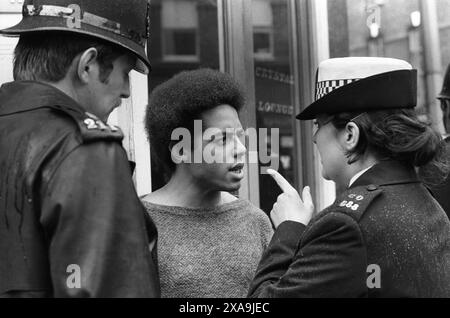 La loi sus, permettait à la police d'arrêter et de fouiller toute « personne soupçonnée » n'importe où, n'importe quand. La policière du Groupe de patrouille spécial donne un jeune noir un remue-doigt. Kings Road, Chelsea, Londres, Angleterre 1977. ANNÉES 1970 ROYAUME-UNI HOMER SYKES Banque D'Images