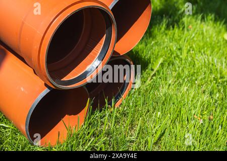 Gros plan photo de tuyaux pour les égouts externes posés sur l'herbe verte par une journée ensoleillée, des éléments du système d'égouts souterrain extérieur Banque D'Images