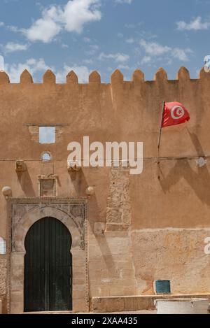 Drapeau national tunisien flottant de l'intérieur des anciens remparts de la médina médiévale de Sfax sur la côte méditerranéenne de la Tunisie, en Afrique du Nord Banque D'Images