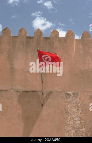 Drapeau national tunisien flottant de l'intérieur des anciens remparts de la médina médiévale de Sfax sur la côte méditerranéenne de la Tunisie, en Afrique du Nord Banque D'Images