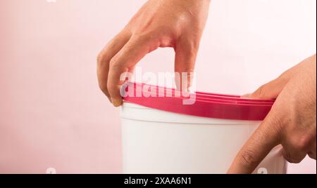 L'homme enlevant le couvercle en plastique sur un seau blanc Banque D'Images