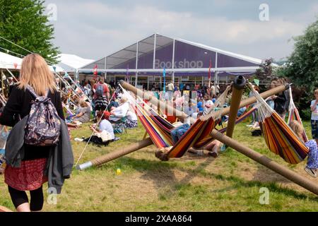 Enfants jouant sur des hamacs les gens dans le jardin se relaxant à l'extérieur Book Shop Hay Literary Festival Hay-on-Wye Wales UK 2024 Grande-Bretagne KATHY DEWITT Banque D'Images