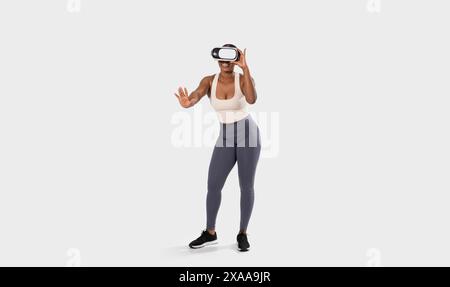 Femme portant casque VR et activewear interagissant avec la réalité virtuelle Banque D'Images