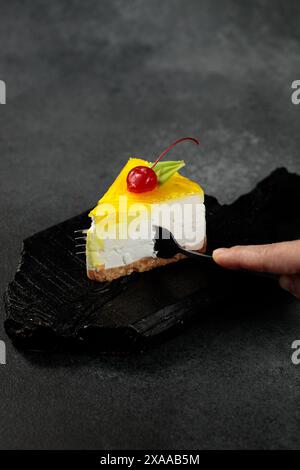 Cheesecake au citron garni de cerises, placé sur un fond noir élégant. Un régal visuel appétissant parfait pour les amateurs de desserts et de plats culinaires Banque D'Images