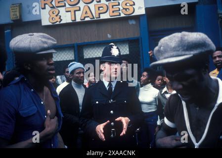 Émeute du carnaval de Notting Hill le lundi 1976 août jour férié. Un policier entouré de jeunes noirs tente calmement de descendre la foule, il y a des violences potentielles. Il essaie de raisonner et de parler aux jeunes noirs britanniques de la communauté. Notting Hill, Londres, Angleterre 30 août. Angleterre des années 1970 Royaume-Uni HOMER SYKES Banque D'Images