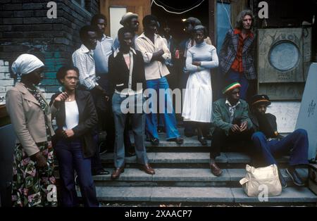 Jeunes adultes noirs britanniques au carnaval de Notting Hill devant un bâtiment communautaire où le système de son de musique reggae est joué. Un homme blanc, harmonie raciale. Notting Hill, Londres, Angleterre 27 août 1979. ANNÉES 1970 ROYAUME-UNI HOMER SYKES Banque D'Images