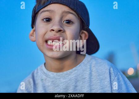 portrait de garçon latin avec chapeau montrant ses dents de bébé manquantes dans le fond le ciel ciel bleu ciel Banque D'Images