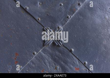 photographie rapprochée d'un détail de portail médiéval en métal gris peint avec rivets et fleur décorative Banque D'Images