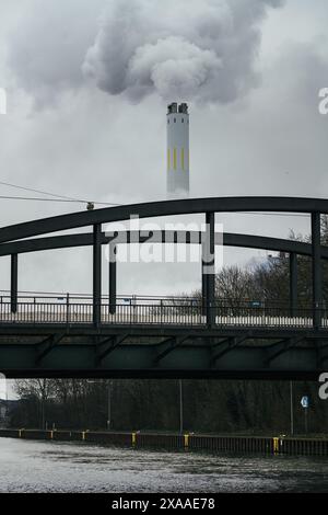 La fumée blanche s'écoule d'une tour à pipe avec un pont au premier plan Banque D'Images