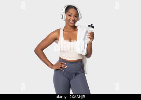 Femme en vêtements d'entraînement tenant une bouteille d'eau et portant un casque Banque D'Images