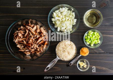 Ingrédients du risotto aux champignons sur une table en bois : riz arborio non cuit avec champignons shiitake crus, oignons et céleri coupés en dés, vin blanc, et plus encore Banque D'Images