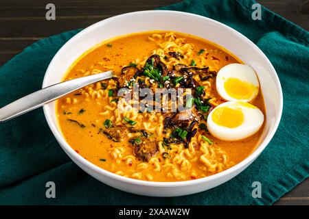 Ramen au curry à la noix de coco avec œuf bouillie et champignons : nouilles ramen de style thaïlandais dans un bouillon chaud et épicé garnies de champignons shiitake Banque D'Images