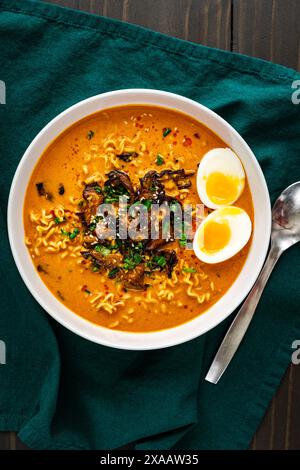 Ramen au curry à la noix de coco avec œuf bouillie et champignons : nouilles ramen de style thaïlandais dans un bouillon chaud et épicé garnies de champignons shiitake Banque D'Images