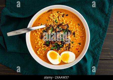 Ramen au curry à la noix de coco avec œuf bouillie et champignons : nouilles ramen de style thaïlandais dans un bouillon chaud et épicé garnies de champignons shiitake Banque D'Images