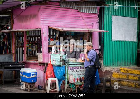 Vendeur Raspado vendant la boisson rafraîchissante typique faite de glace pilée recouverte de sirop de fruits fait maison, et un client au marché de Santa Ana, E. Banque D'Images