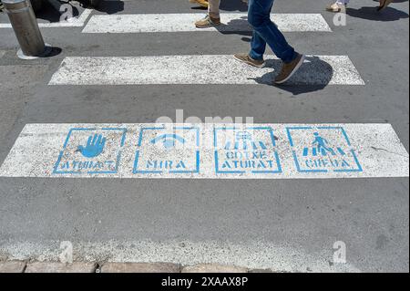 Sitges, Barcelone, Espagne-05 juin 2024 : image de traversée de zèbre avec des icônes éducatives pour traverser correctement et promouvoir la sécurité routière dans la ville. Banque D'Images