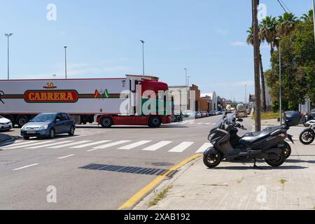 Barcelone, Espagne - 8 juin 2023 : un gros camion semi-remorque tourne à gauche à un carrefour en Espagne. Un scooter est garé sur le trottoir de la R Banque D'Images