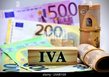 Pièce en bois avec le texte "IVA" représente une taxe italienne avec des billets de banque européens comme arrière-plan. Banque D'Images