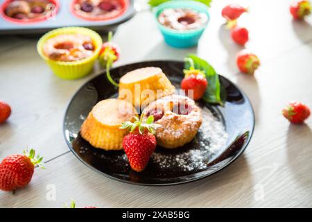 Muffins au lait caillé sucré garnis de fraises, dans une assiette sur une table en bois. Banque D'Images