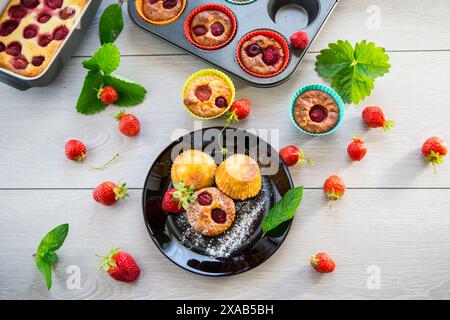 Muffins au lait caillé sucré garnis de fraises, dans une assiette sur une table en bois. Banque D'Images