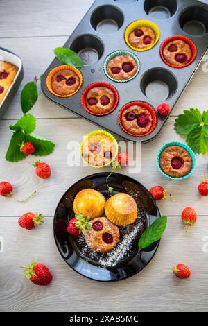 Muffins au lait caillé sucré garnis de fraises, dans une assiette sur une table en bois. Banque D'Images