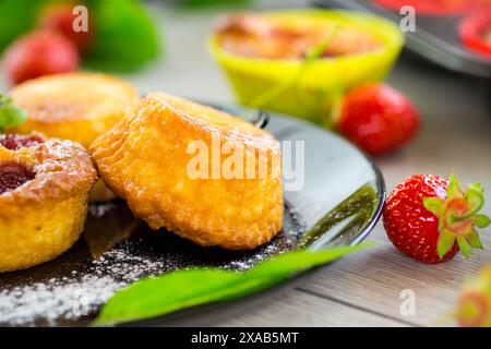 Muffins au lait caillé sucré garnis de fraises, dans une assiette sur une table en bois. Banque D'Images
