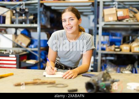 La femme employée de l'entrepôt du magasin prend des notes dans un carnet, garde trace des marchandises Banque D'Images