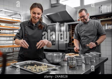 Homme et femme préparant des baguettes françaises en cuisine Banque D'Images