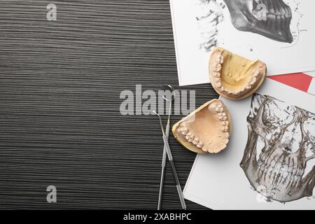 Modèle dentaire avec gencives, outils de dentiste, diagrammes anatomiques et espace pour le texte sur la table en bois gris, pose à plat. Fonte de dents Banque D'Images