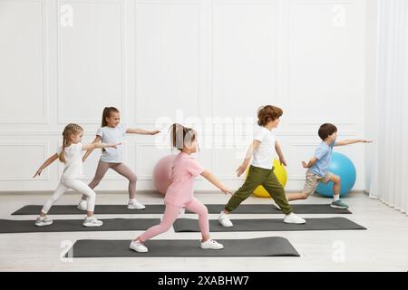 Groupe d'enfants faisant des exercices de gymnastique sur des tapis à l'intérieur Banque D'Images