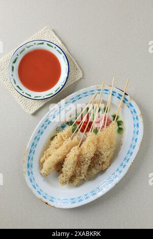 Cilor ACI Telor, brochette de boules de tapioca frites enveloppée de pâte à œufs croustillants. Servi avec une sauce épaisse rouge épicée Banque D'Images