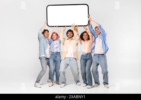 Groupe diversifié de jeunes adultes tenant un smartphone vierge Banque D'Images