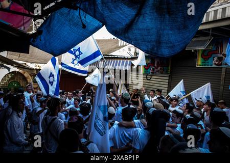 Des jeunes israéliens de droite chantent la danse et brandissent leur drapeau national dans le quartier musulman de Jérusalem, jeudi 5 juin 2024. Des dizaines de milliers de jeunes religieux ultranationalistes sionistes, hommes et femmes, ont défilé à travers les parties musulmanes de la vieille ville de Jérusalem lors de la marche annuelle du drapeau du jour de Jérusalem, un événement qui menace de déclencher de nouvelles violences dans la guerre Israël-Hamas. La journée de Jérusalem marque la réunification de la ville pendant la guerre des six jours et la IsraelÕs prise du Mont du Temple et du mur occidental, JudaismÕs lieux les plus saints. Photo par Eyal Warshavsky. Banque D'Images