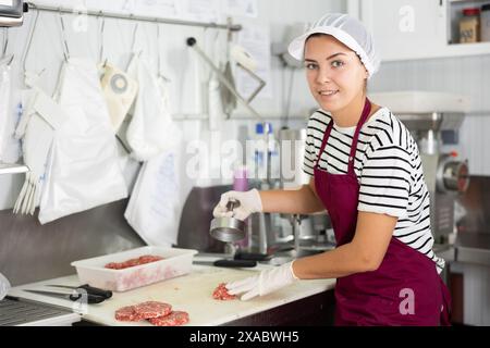 Cuisson des produits semi-finis - fille prépare les côtelettes de viande à l'aide de dispositifs spéciaux Banque D'Images
