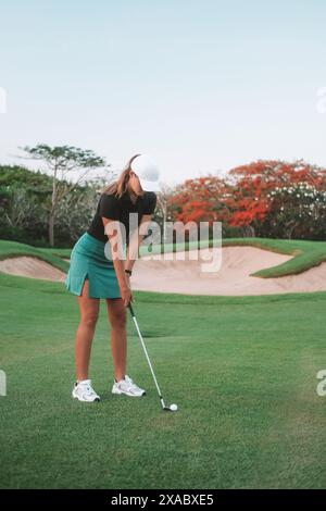 Une jeune femme joue au golf professionnellement dans la jupe de sport et la casquette qu'elle tient un club Banque D'Images