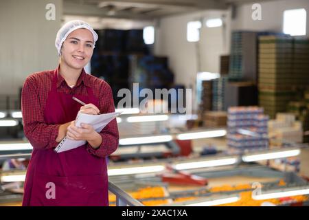 Jeune femme superviseure avec des papiers inspectant l'atelier de tri des mandarins Banque D'Images