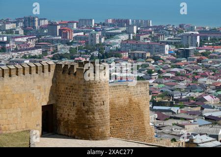 DERBENT, RUSSIE - 09 MAI 2024 : la tour et le mur de l'ancienne forteresse de Naryn-Kala sur fond de la ville moderne sur un jour de mai ensoleillé. Banque D'Images