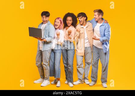Groupe d'amis enthousiaste célébrant le succès avec Laptop Banque D'Images