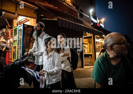 Jérusalem, Israël. 05 juin 2024. Une famille religieuse israélienne passe devant un magasin palestinien près de la porte de Damas à Jérusalem. Des dizaines de milliers de jeunes religieux ultranationalistes sionistes, hommes et femmes, ont défilé à travers les parties musulmanes de la vieille ville de Jérusalem lors de la marche annuelle du drapeau du jour de Jérusalem, un événement qui menace de déclencher de nouvelles violences dans la guerre Israël-Hamas. La journée de Jérusalem marque la réunification de la ville pendant la guerre des six jours et la Israelís prise du Mont du Temple et du mur occidental, Judaismís lieux les plus saints. Crédit : SOPA images Limited/Alamy Live News Banque D'Images