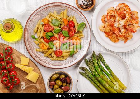 Une délicieuse assiette de pâtes italiennes ornée de tomates fraîches et de feuilles de basilic aromatiques. Pose à plat Banque D'Images