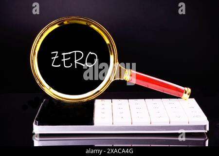 Texte ZÉRO est apparu à travers une loupe sur un fond noir debout sur une calculatrice Banque D'Images