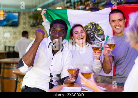 Des amis se sont réunis pour assister au championnat de football et célébrer avec des verres de bière. Fille tenant le drapeau du Mexique Banque D'Images