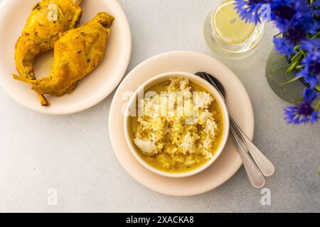 Ragoût de lapin avec du riz, du brocoli et des gâteaux de riz, une table servie avec de la nourriture et un vase de fleurs, un délicieux déjeuner copieux ou dîner Banque D'Images