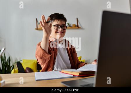 Garçon atteint du syndrome de Down au bureau à domicile à l'aide d'un ordinateur portable. Banque D'Images