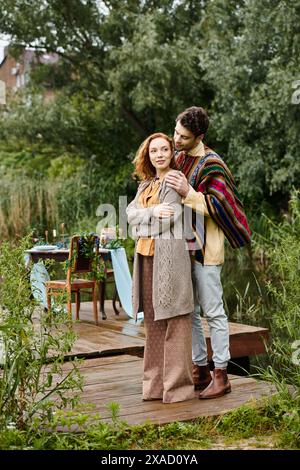 Un homme et une femme, vêtus de vêtements de style boho, se tiennent sur un quai au bord d'un lac serein. Banque D'Images