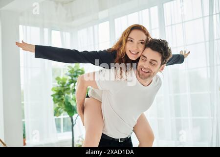 Un homme porte gracieusement une femme sur son dos dans un moment tendre et intime entre le couple. Banque D'Images