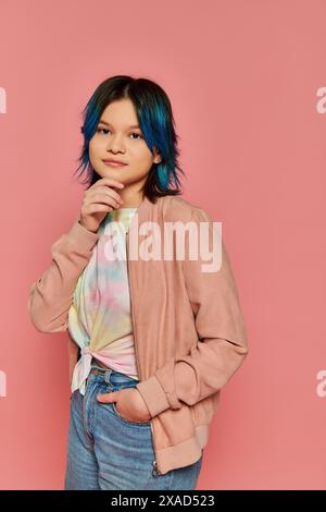 Une fille aux cheveux bleus saisissants se tient en toute confiance devant un mur rose vif, exsudant créativité et individualité. Banque D'Images