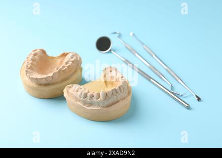 Modèle dentaire avec gencives et outils de dentiste sur fond bleu clair. Fonte de dents Banque D'Images