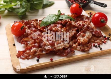 Tranches de bacon frit savoureux avec différentes épices et tomates sur une table en bois Banque D'Images